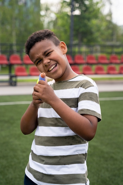 Ragazzo sorridente a tiro medio che gioca con la pistola ad acqua