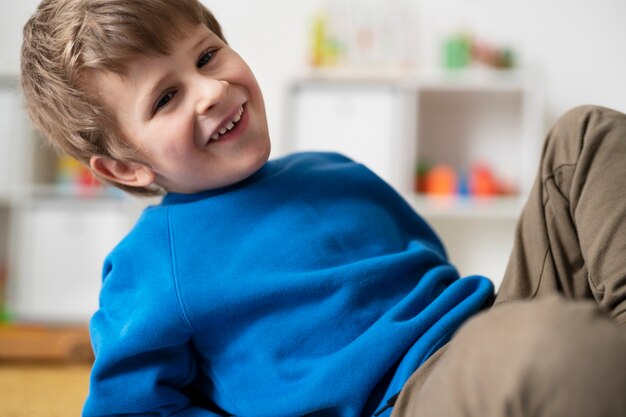 Medium shot smiley boy sitting indoors