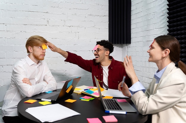 Free photo medium shot smiley colleagues sticking post its