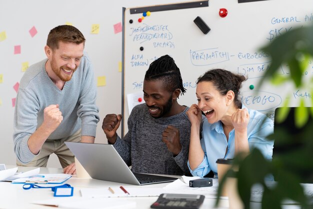 Medium shot smiley colleagues with laptop