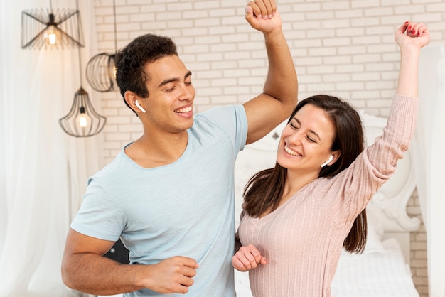 Medium shot smiley couple dancing in the bedroom