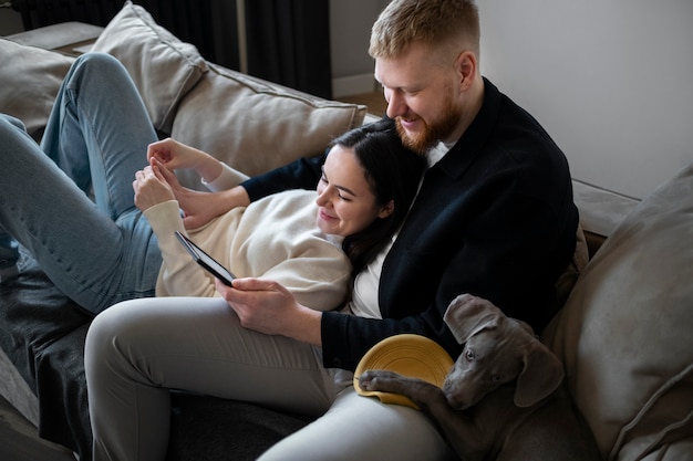 Free photo medium shot smiley couple and dog indoors