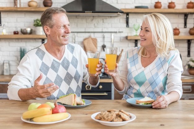 Medium shot smiley couple in the kitchen having a toast