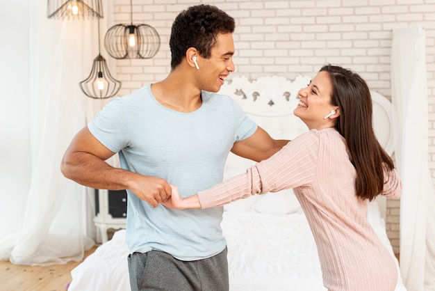 Medium shot smiley couple listening to music in bedroom