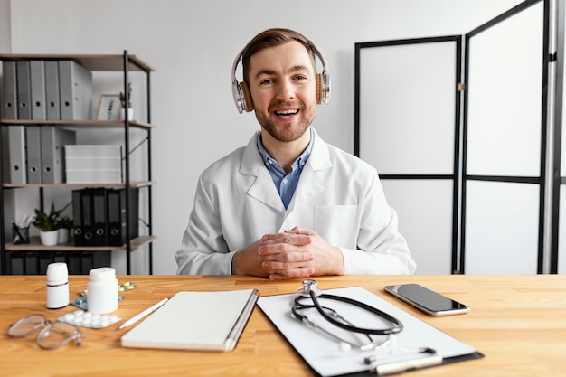 Free photo medium shot smiley doctor at desk