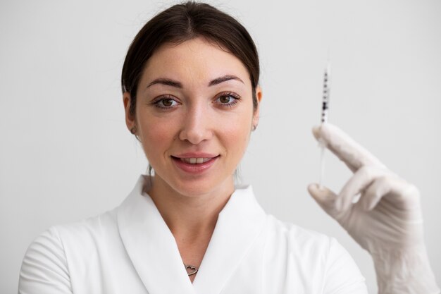 Medium shot smiley doctor holding syringe