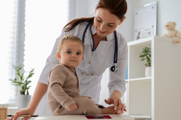 Medium shot smiley doctor weighing baby