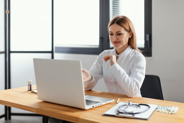 Foto gratuita medico di smiley del colpo medio con il computer portatile