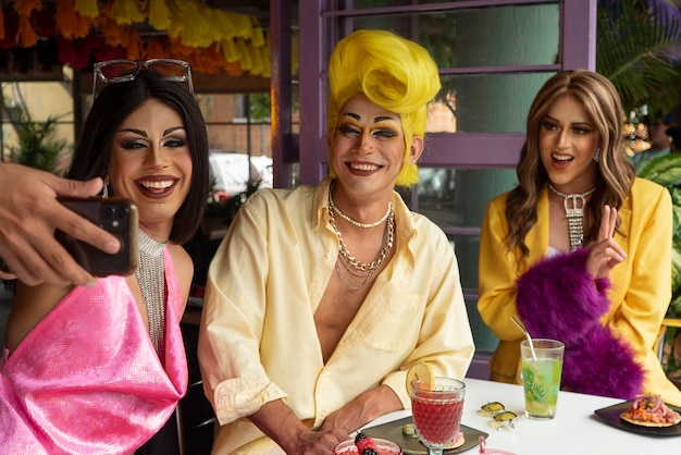 Medium shot smiley drag queens taking selfie