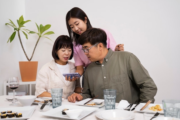 Free photo medium shot smiley family looking at smartphone