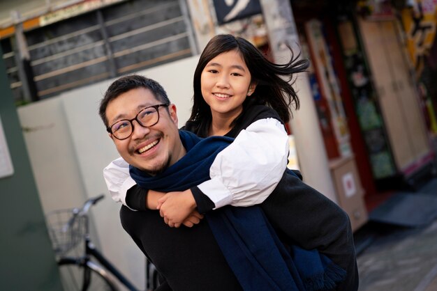 ミディアムショットのスマイリー父が女の子を運ぶ