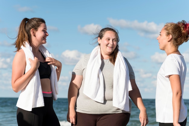 Medium shot smiley fitness friends at seaside