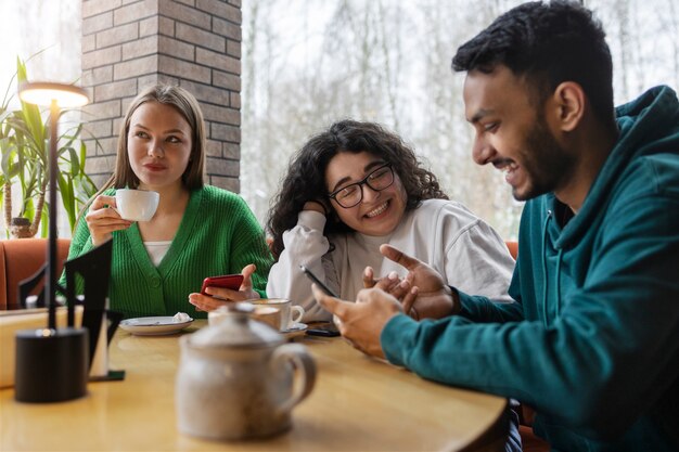 Medium shot smiley friends with smartphone