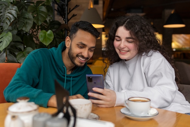 Medium shot smiley friends with smartphone