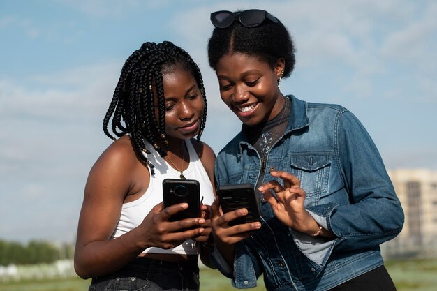 Medium shot smiley friends with smartphones