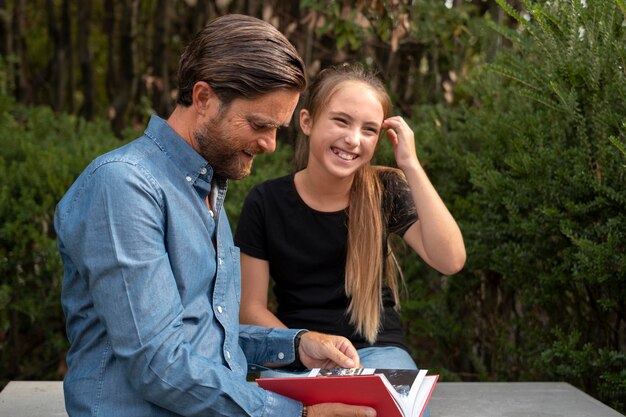 Medium shot smiley girl and father with book