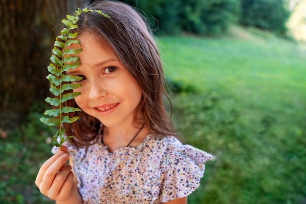 Foto gratuita foglia della holding della ragazza di smiley del colpo medio