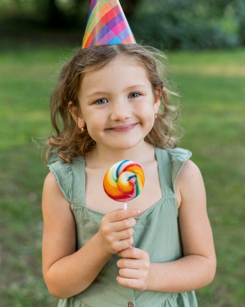 Foto gratuita lecca-lecca della holding della ragazza di smiley del colpo medio