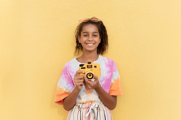 Ragazza sorridente con colpo medio che tiene la macchina fotografica