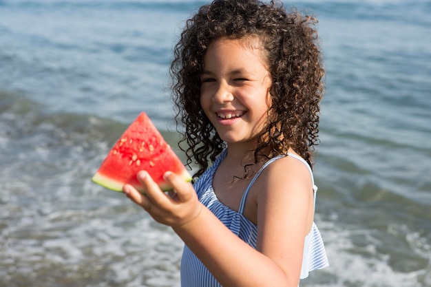 Medium shot smiley girl holding watermelon