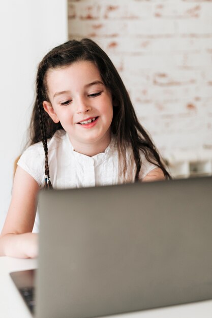 Medium shot smiley girl looking at her laptop