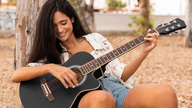 중간 샷 웃는 소녀 기타 연주