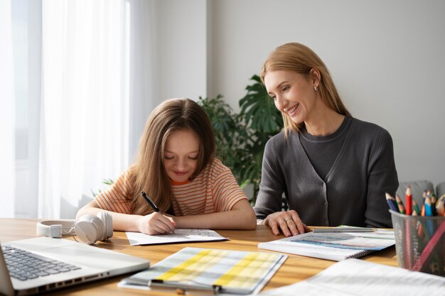 Medium shot smiley girl and teacher inside