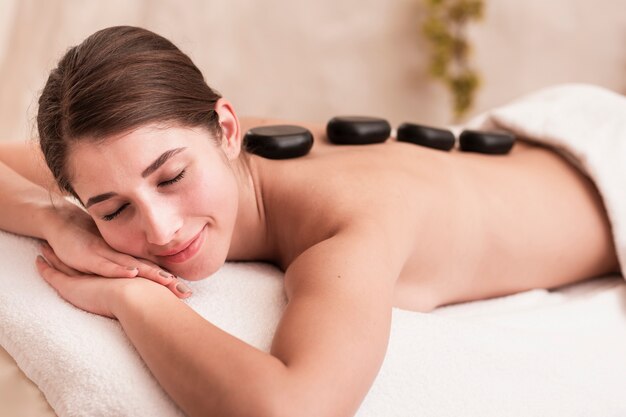 Medium shot smiley girl trying stone spa treatment