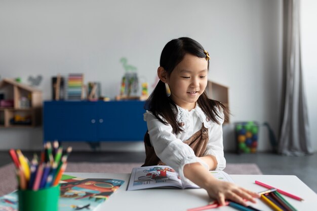 Medium shot smiley girl with coloring book