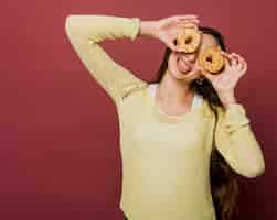 Free photo medium shot smiley girl with doughnuts and red background