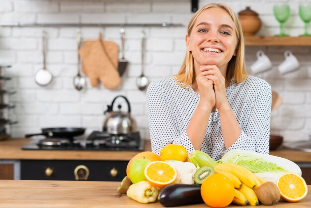 Medium shot smiley girl with fruits in the kitchen