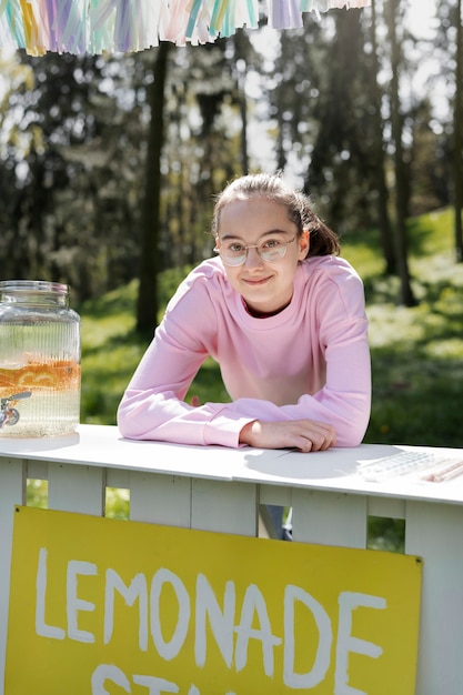 Medium shot smiley girl with lemonade stand