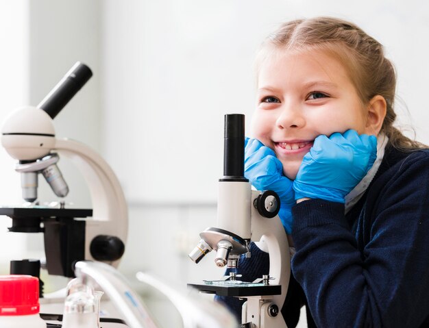 Medium shot smiley girl with microscope