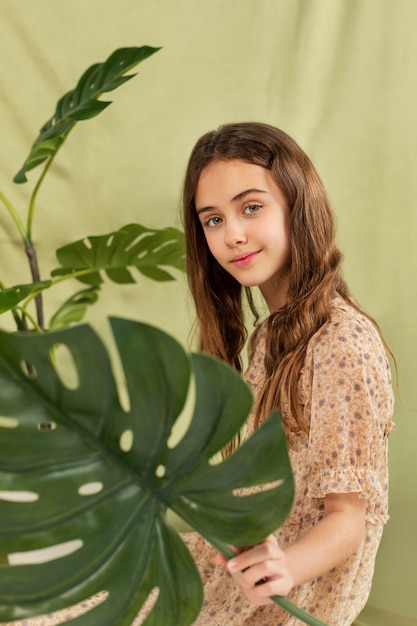 Free photo medium shot smiley girl with monstera plant