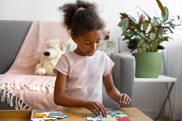 Free photo medium shot smiley girl with puzzle pieces