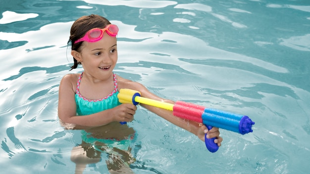 Medium shot smiley girl with water gun