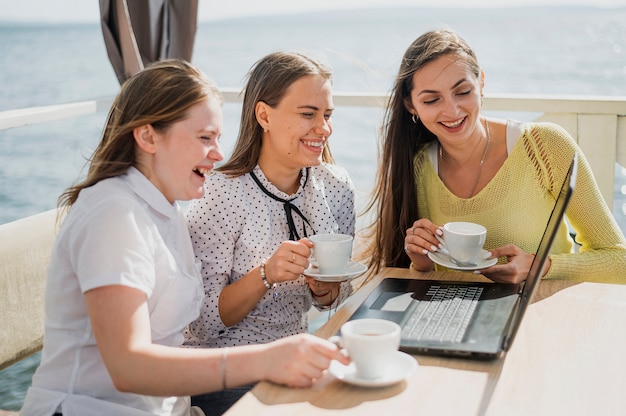 Free photo medium shot smiley girls with cups and laptop