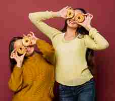 Free photo medium shot smiley girls with doughnuts