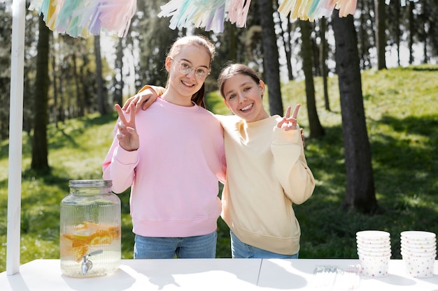 Medium shot smiley girls with lemonade stand