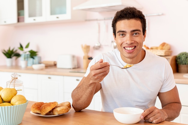 Free photo medium shot smiley guy eating cereals