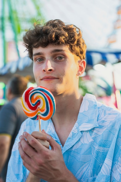 Medium shot smiley guy holding lollipop 