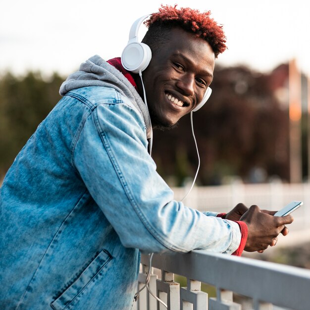 Medium shot smiley guy with headphones outdoors