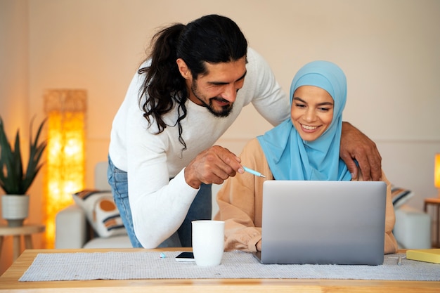 Free photo medium shot smiley islamic couple with laptop