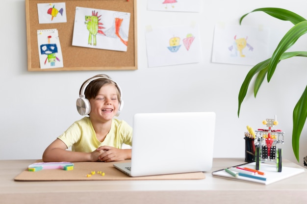 Medium shot smiley kid looking at laptop