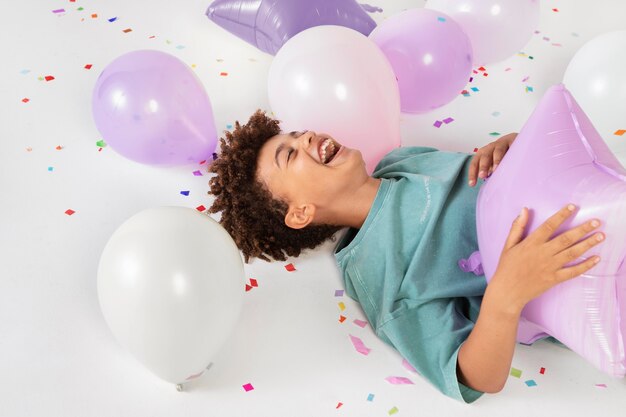 Улыбающийся ребенок среднего кадра, играющий с воздушными шарами