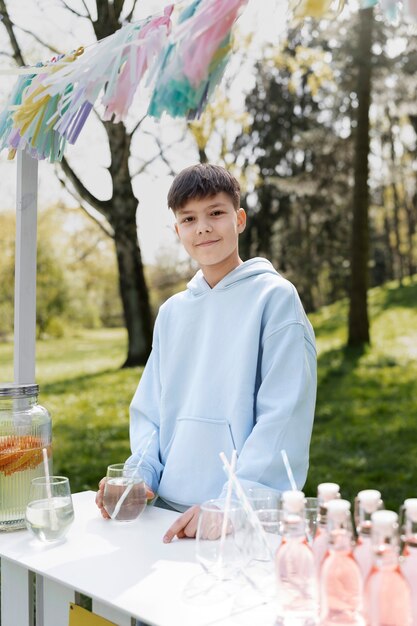 Medium shot smiley kid selling lemonade
