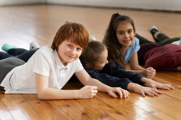 Free photo medium shot smiley kids laying on floor