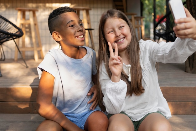 Foto gratuita bambini sorridenti di colpo medio che prendono selfie