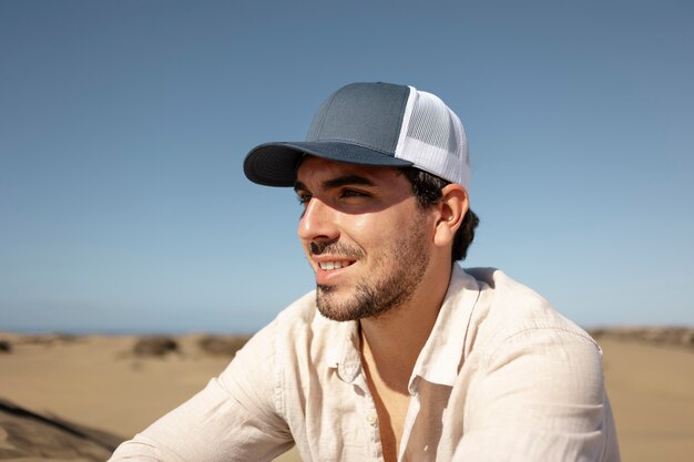 Medium shot smiley man in desert with trucker hat