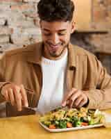 Free photo medium shot smiley man eating food